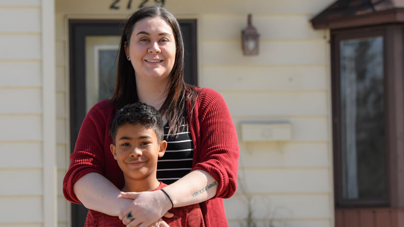 Brittany and her son Ayden in front of their home