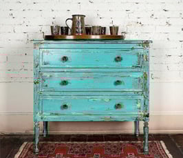 Refurbished teal dresser with distress markings.