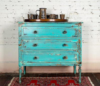 Refurbished teal dresser with distress markings.