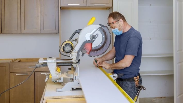 Measuring lumber next to a circular saw.