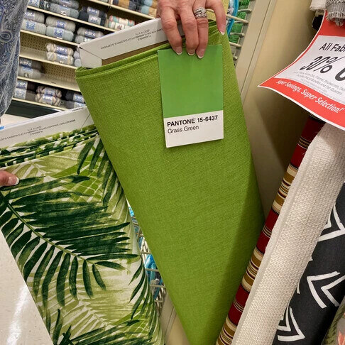 A new lime green bolt of fabric, labeled "Pantone 15-6437 - Grass green."