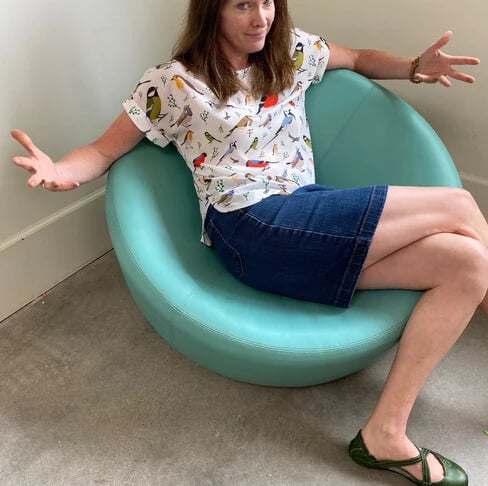 Rae in a round chair.