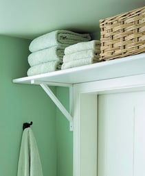 High shelf with towers and a basket in a bathroom.