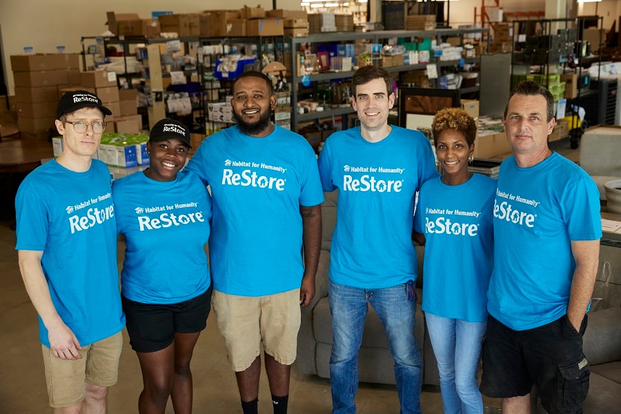 Six ReStore employees in blue t-shirts posing and smiling