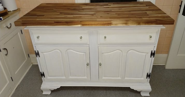 A buffet painted white with a dark stain butcher block on top