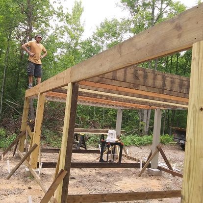 Derek standing on the beams of his constructed cabin
