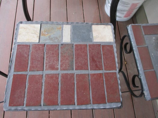 Two small patio table tops made with different colors of brick and tile