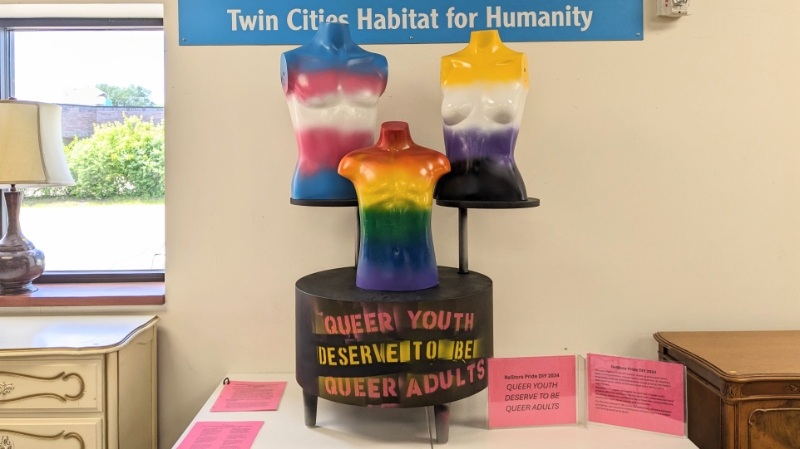 Display of three mannequin painted in LGBTQ colors.