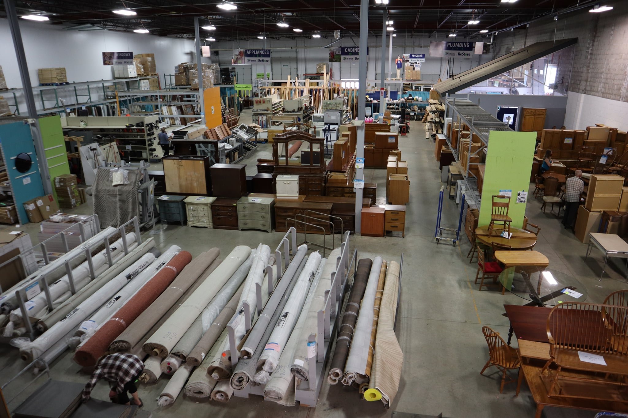 Overhead view of the Minneapolis ReStore sales floor with rolls of carpet, and rows of cabinets and furniture.