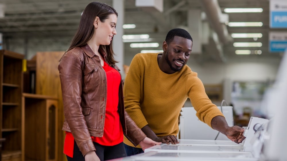A couple looking over a washer-dryer machine for sale at ReStore.