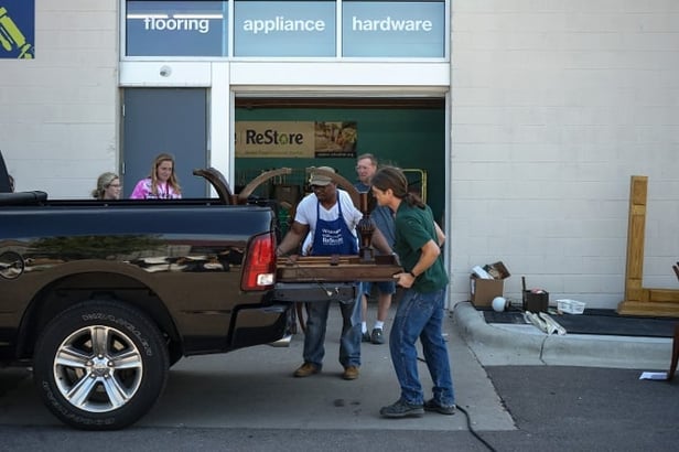 ReStore worker helping unload items from the back of a pickup truck.