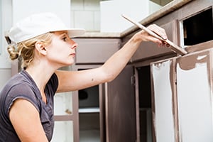 a woman painting kitchen cabinets