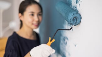Woman painting a wall using a roller.