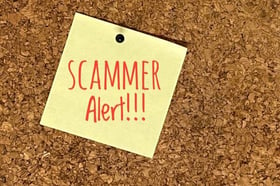 Image of yellow post-it with "Scammer alert" in red writing.