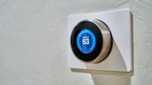 Digital thermostat mounted on a white wall.