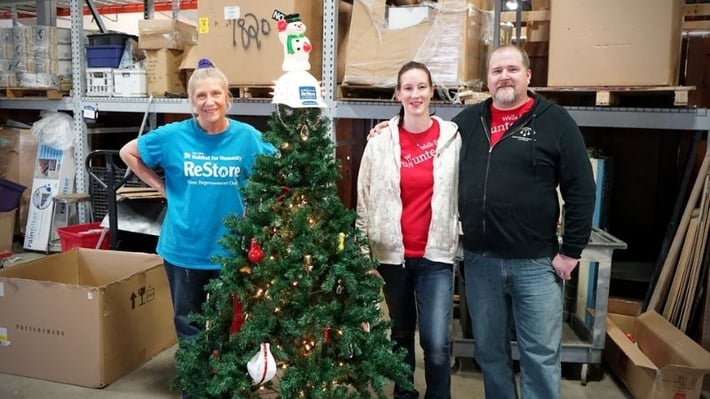 ReStore volunteers behind a small Christmas tree.