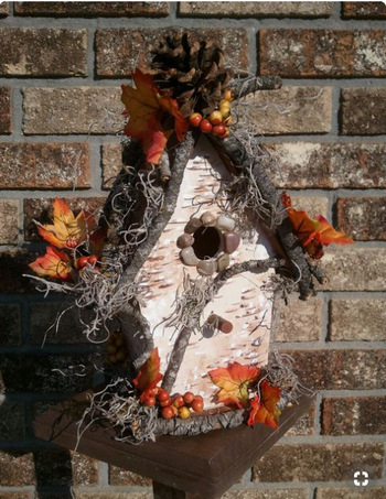 Birdhouse decorated with leaves and twigs.