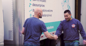 Two people shaking hands next to the ReStore truck.