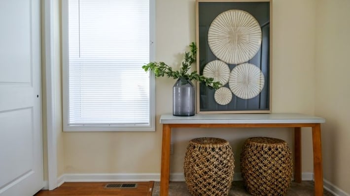 Entryway with table, baskets, flowers, and art.