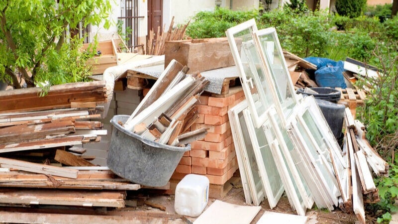 Piles of lumber and bricks in front of a house.