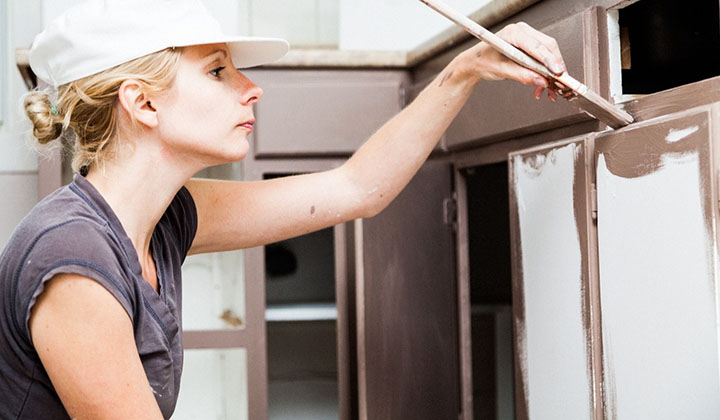 woman painting kitchen cabinets brown 