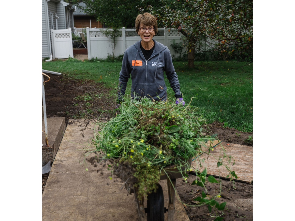 ReStore employee pushing a wheelbarrow of leaves and twigs.