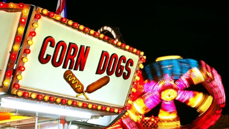 A ferris wheel and a sign for corn dogs.