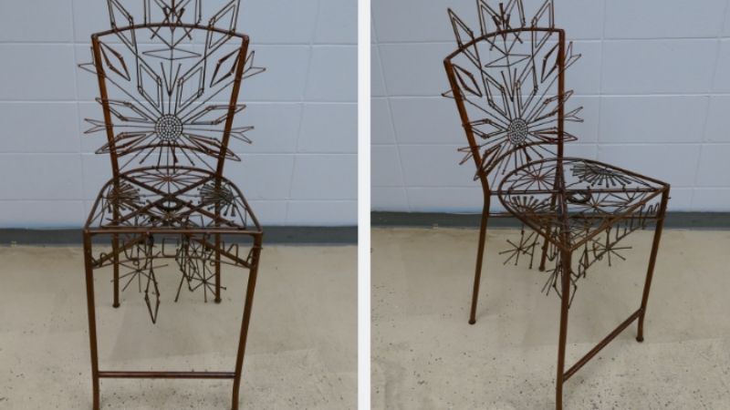 A metal chair with designs made out of nails.