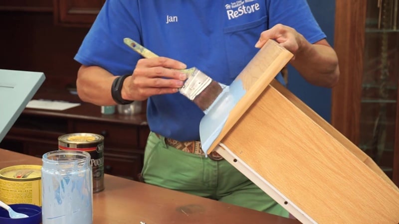 ReStore staff member painting a drawer.