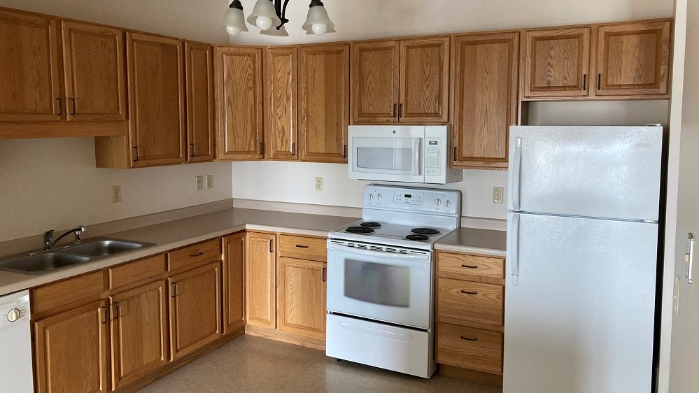 Cabinets, stove, and fridge in senior living apartment.